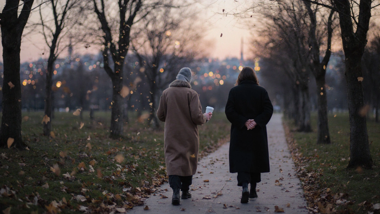 Sonbahar yapraklarıyla kaplı bir parkta yavaş yürüyen iki kişi.
