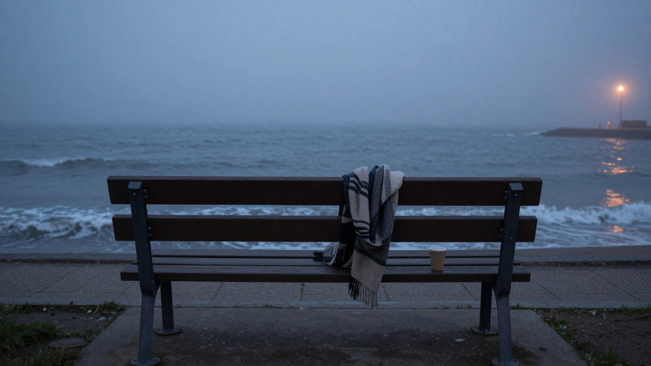 Boş bir bankta bırakılmış bir atkı ve kahve kupası, deniz kıyısında.