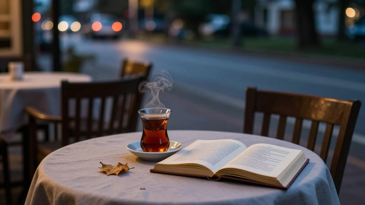 Boş bir kanepe üzerinde bir fincan çay ve açılmış bir şiir kitabı, karanlık bir kafe masasında.