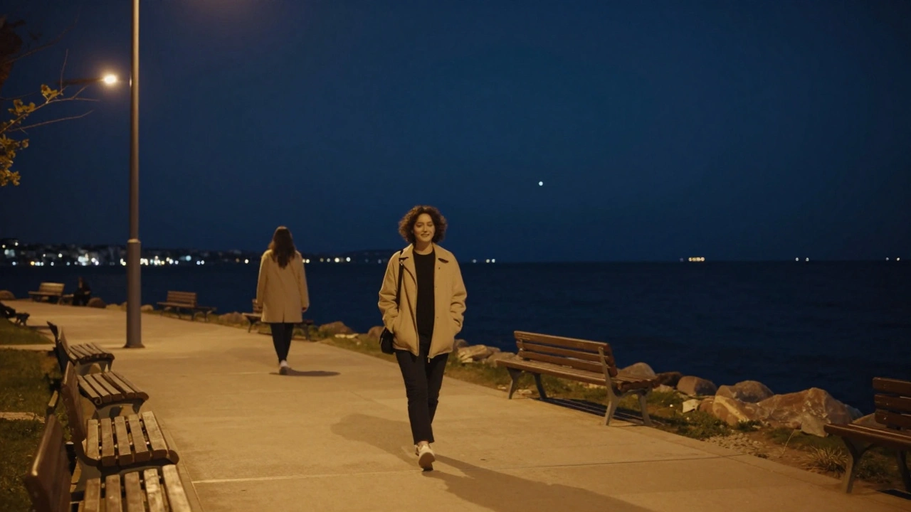 Bir kişi Maltepe'nin aydınlatılmış sahil yolu boyunca hafif gülümseyerek yürüyor, uzakta başka bir figür sessizce yürüyor.
